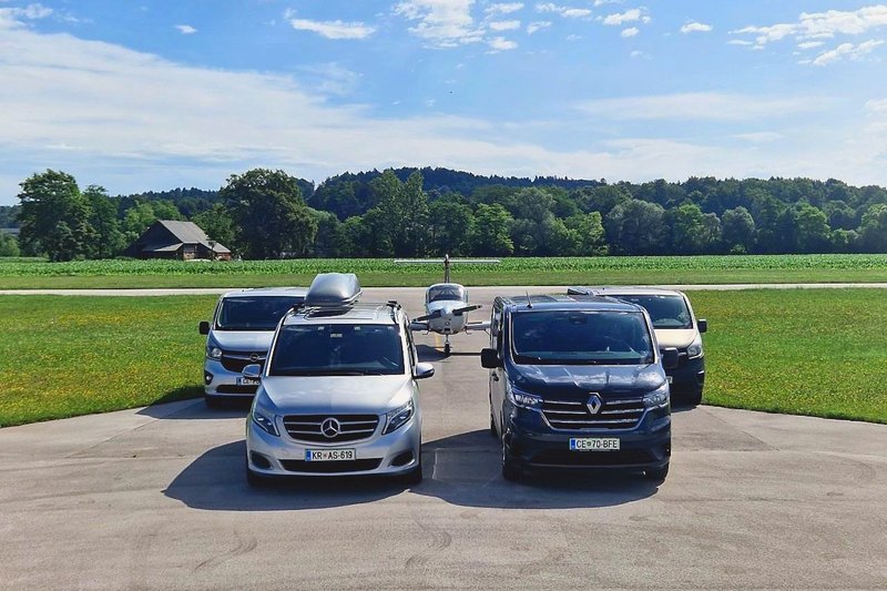 Mercedes V-Class и Renault Trafic на аэродроме, за ними ещё два микроавтобуса и самолёт