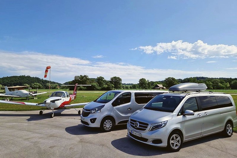Mercedes V-Class с багажным боксом и Opel Vivaro рядом с самолётами на аэродроме